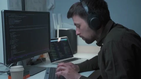 Young male software developer with headsets working, typing on the keyboard and Stock Footage 230989634