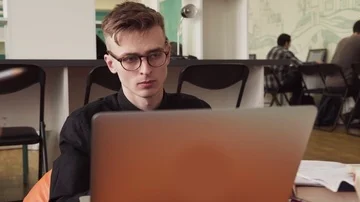 Young male student in glasses using laptop in university Stock Footage 85909312