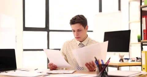 Young male student intern studies documents in office Stock Footage 234593450