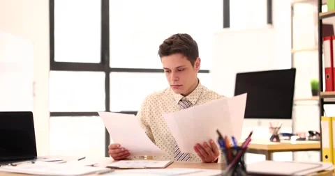 Young male student intern studies documents in office Stock Footage 256293237