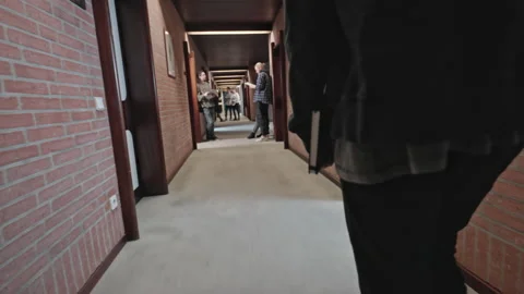 Young male student walking down the hallway of his school with a book in hand Stock Footage