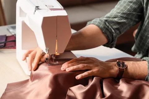 Young male tailor using sewing machine in atelier, closeup Stock Photos