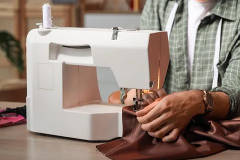 Young male tailor using sewing machine in atelier, closeup Stock Photos