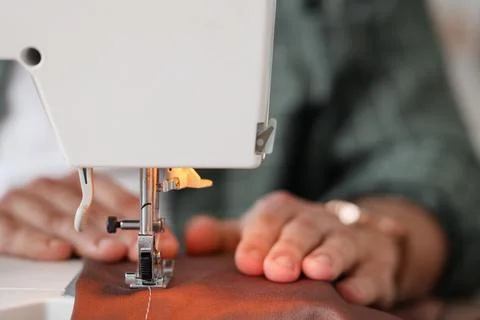 Young male tailor using sewing machine in atelier, closeup Stock Photos