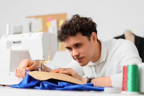 Young male tailor using sewing machine in atelier Stock Photos