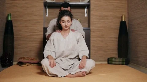 Young male thai massagist is massaging young woman's back and shoulders sitting Stock Footage