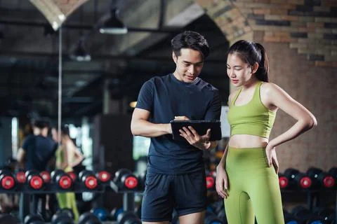 Young male trainer using tablet for schedule exercise training to fitness fem Stock Photos