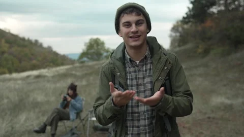 Young male v-logger talking to camera while camping in nature Video stock 319783371