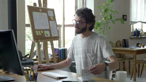 Young male working in front of computer at his cosy stylish house, flat, Stock Footage 245424315