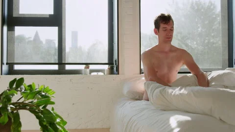 Young man in 20s sits up cracks neck and begins to get out of bed Stock Footage 147473722