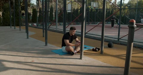 A Young Man is Actively Engaged in a Physical Workout Routine in an Outdoor Gym Stock Footage 317836537
