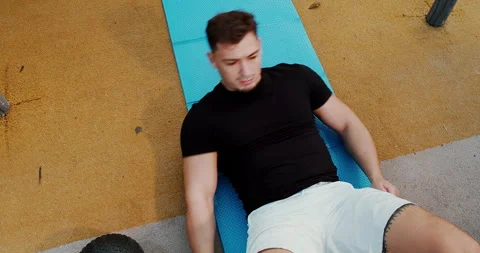 A young man is actively exercising on a mat in a wellequipped gym environment Stock Footage 317981997