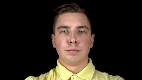 The young man actively moves his lips. A man stands on a black background. A man Stock Footage 123314710