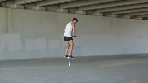 Young man actively spending time with spring stick. Gray concrete walls around. Stock Footage 68756116