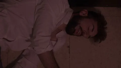 Young man addicted to alcohol lying on the floor in the throes of hallucinations Stock Footage 197747473