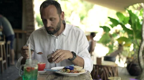 Young man adding brown sugar to coffee during breakfast, 4K Stock Footage 68909981