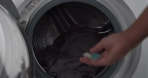 Young man adding laundry detergent to machine load pre-wash Stock Footage 172281418