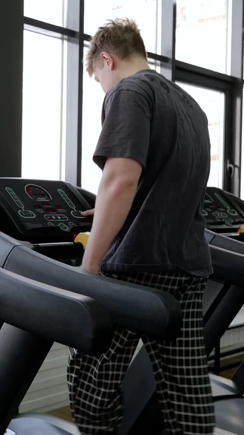 Young man adjusting treadmill console during indoor workout in modern fitness Video stock 339346904