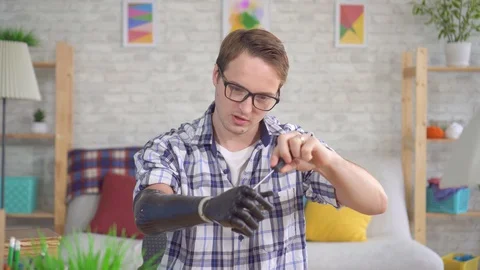 Young man adjusts a bionic prosthetic hand with a screwdriver Stock Footage 119072778