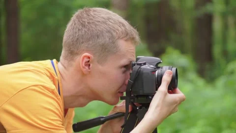 A young man adjusts focus on a mirror camera and takes a picture. Stock Footage 92312053