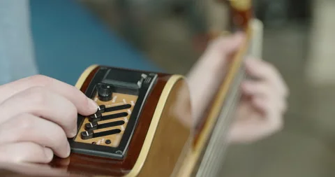 A young man adjusts the sound of a guitar. Close up Vídeos de archivo 130442425