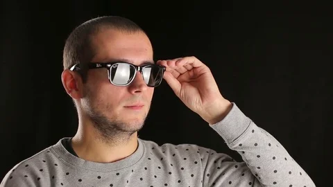 Young man adjusts sunglasses in studio Stock Footage 82919915