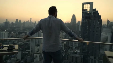 Young man admire beautiful sunset over city at luxury bar Stock Footage 125992575