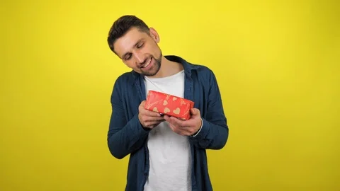 A young man admires the box with a gift in his hands, smiles Stock Footage 119862093
