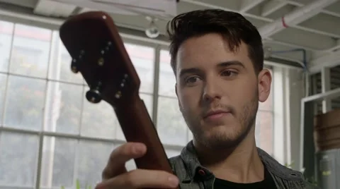 Young man admiring ukulele Stock Footage 64888640