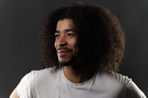 Young man with afro looking away smiling Stock Photos