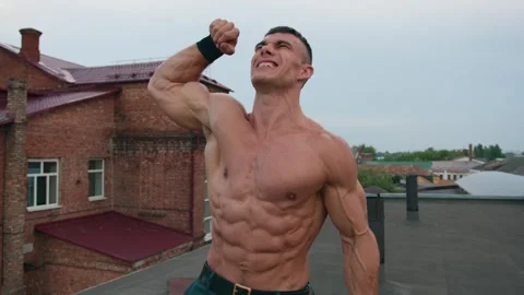 Young man after training with kettlebell on roof of building demonstrates his Видео 247117096