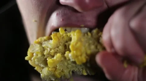 Young man aggressively taking a bite from corn close Stock Footage 58839301
