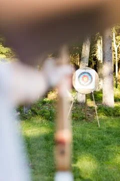 Young Man Aiming Arrow At Target Board In Forest 写真素材