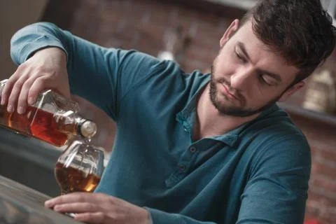 Young man alcoholic social problems concept pouring brandy Foto stock