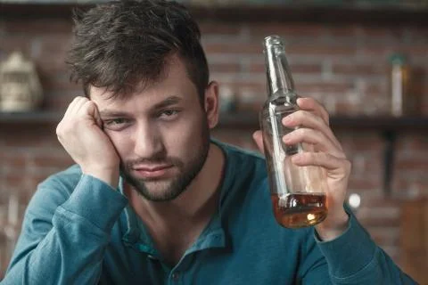 Young man alcoholic social problems concept holding bottle sleepy Stock Photos
