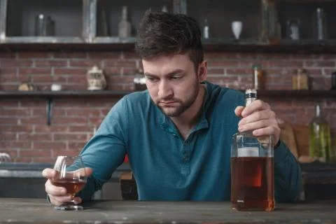 Young man alcoholic social problems concept holding whiskey bottle and glass Stock Photos