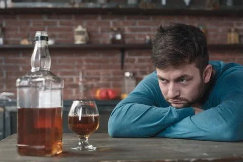 Young man alcoholic social problems concept looking at whiskey Stock Photos