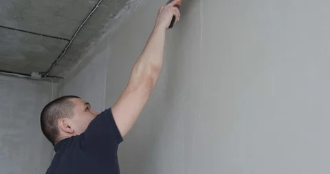 Young man aligns wall, construction equipment. Putty on wall for smooth walls Stock Footage 129836865
