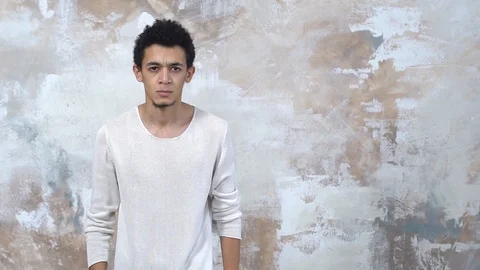 Young man alone isolated on painted wall looking camera angry Stock Footage 121477196