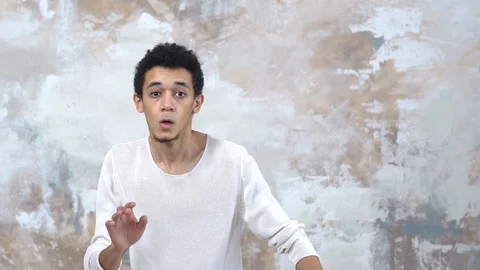 Young man alone isolated on painted wall hands forward careful Stock Footage 121646418