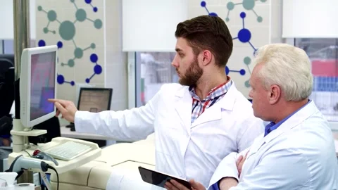 Young man analyzes data on computer and tablet in a modern laboratory Stock Footage 311918755