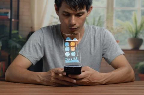 Young Man Analyzing Data on Smartphone with Digital Graphs in Indoor Enviro.. Stock Photos