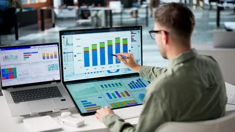 Young Man Analyzing Financial Data On Desktop To Track Business Performance. Stock Photos