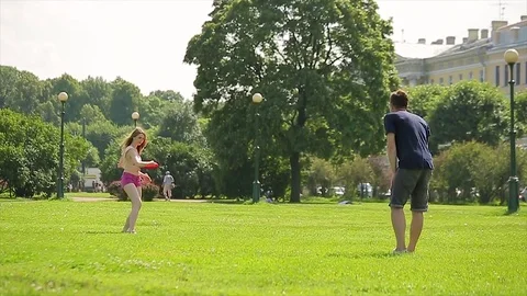 Young man and his attractive girlfriend are playing a frisbee game on a lawn in Stock Footage 75715484