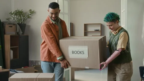 Young Man and His Girlfriend with Bionic Arm Carrying Heavy Box Labeled Books Stock Footage 323301885