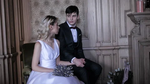 Young man and pretty bride join hands sitting in light room Stock Footage 145536680