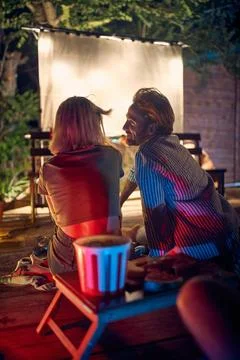 Young man and woman flirting, enjoying their time on outdoor movie night. C.. Stock Photos