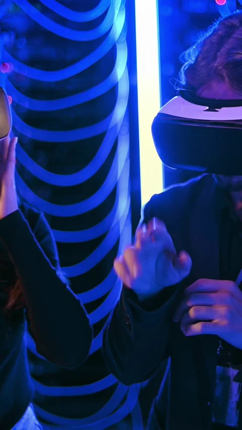 Young man and woman using virtual reality headsets at tech event with neon .. Stock Footage 339344206