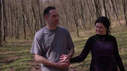 Young man and woman walk through quiet forest holding hands and hugging gently Vidéo 333481353