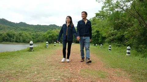 Young man and woman walking holding hands enjoying Stock Footage 114440341